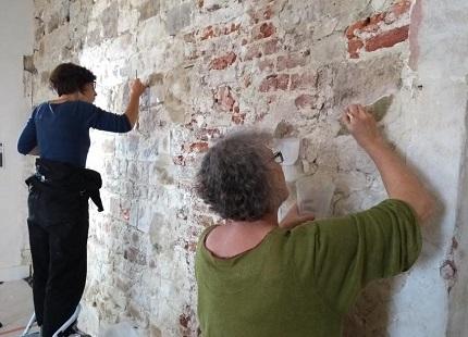 © Pieter Rombouts Linda Van Dijck en Marie-Hélène Ghisdal fixeren zowel de verf als het pleister van de muur.