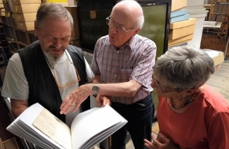 © Pieter Rombouts Vrijwilligers Kristiaan, Leo en Christine bestuderen een boek in het archief.